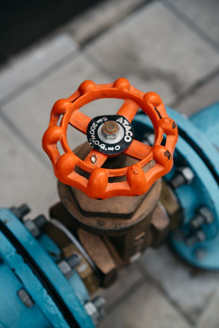 Close-up of orange valve on a blue pipeline, showcasing industrial equipment details.