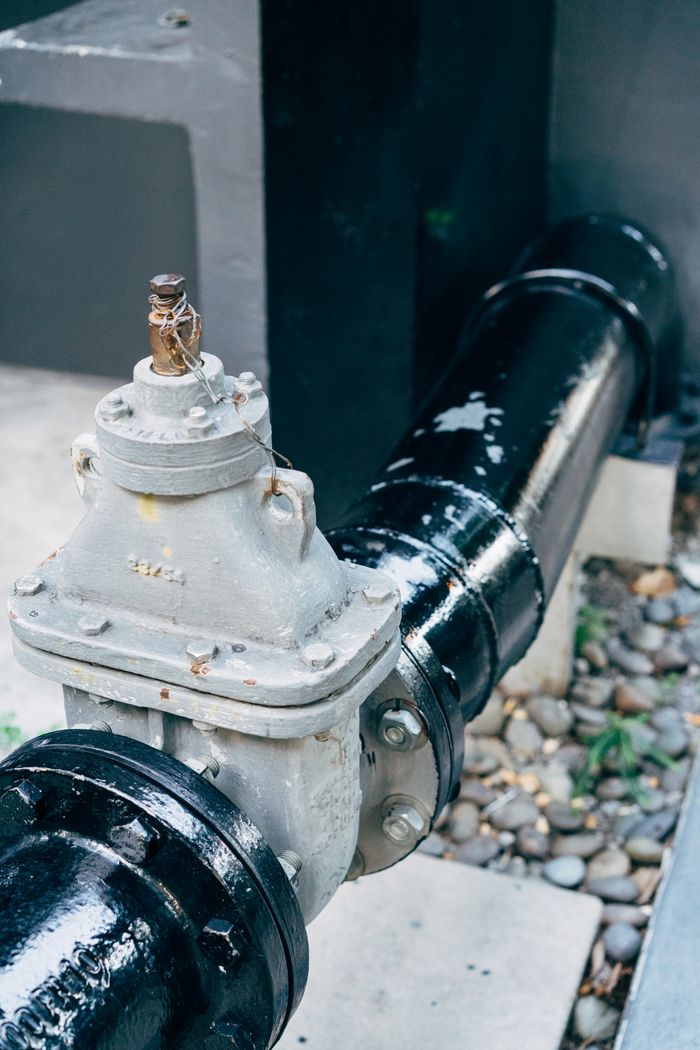 Home Detailed view of a plumbing valve with connected black pipeline, essential for industrial applications.